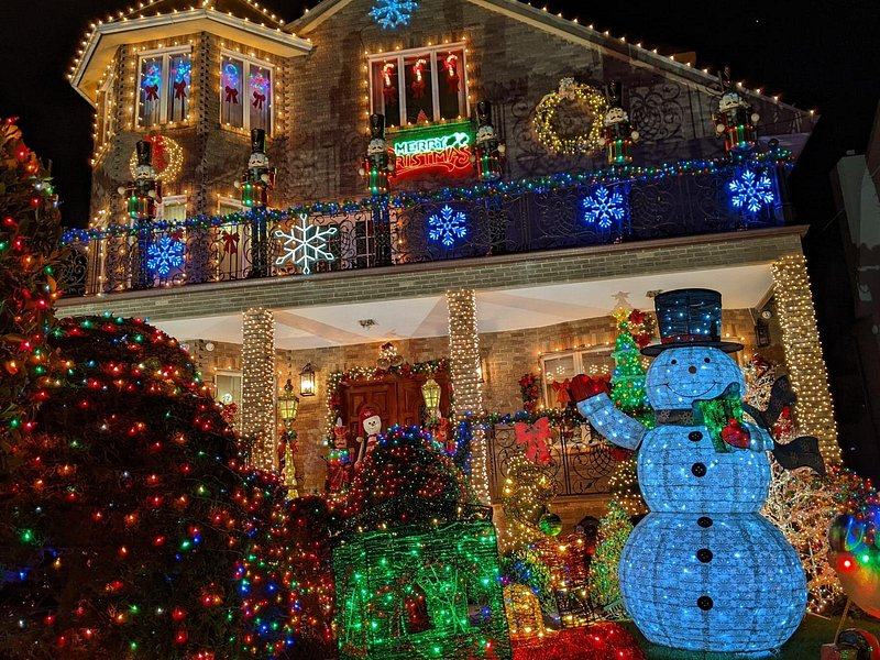 A Dyker Heights house edged in blue and red lights with a large illuminated snowman on the lawn