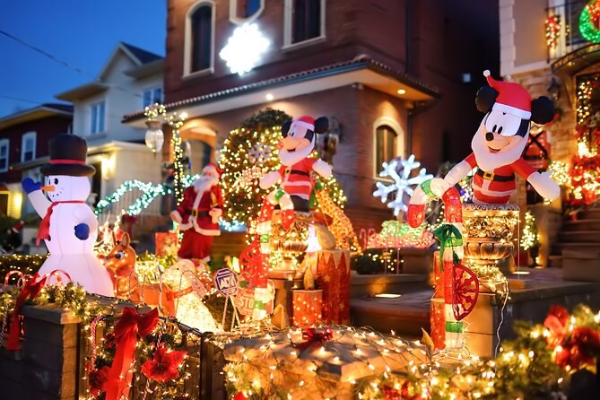A Dyker Heights porch filled with lit snowmen, a Mickey Mouse figure and stacked gift boxes