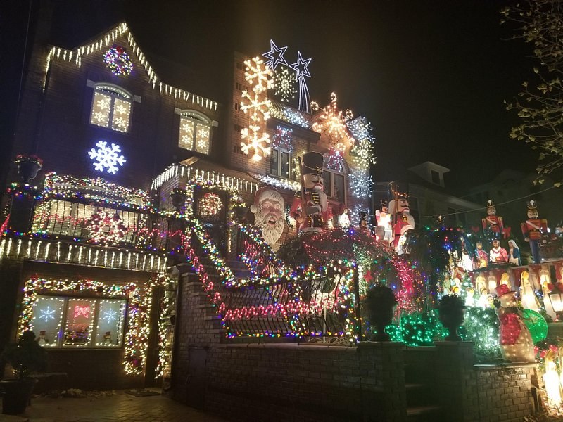 Icicle lights along the gutters of a Dyker Heights house with lit snowflakes on the gable