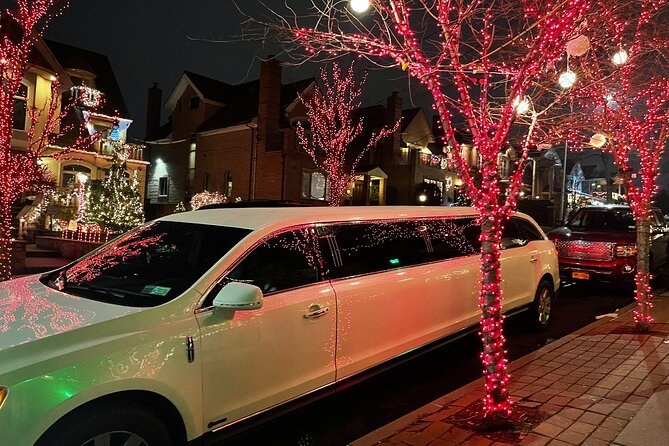 A white stretch limousine parked under a tree wrapped in red lights on a Dyker Heights street