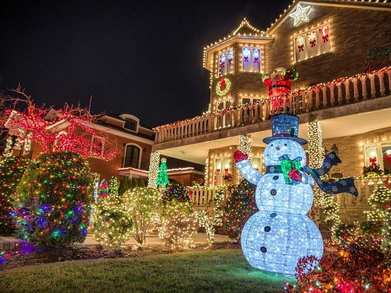 An illuminated snowman on the front lawn of a Dyker Heights house strung with coloured lights